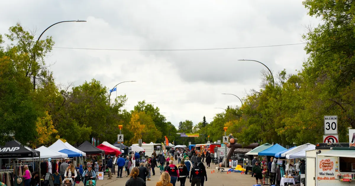 Main Street Camrose closed to traffic, vendor tents lining both kerbs, people walking the centre line under an overcast sky.