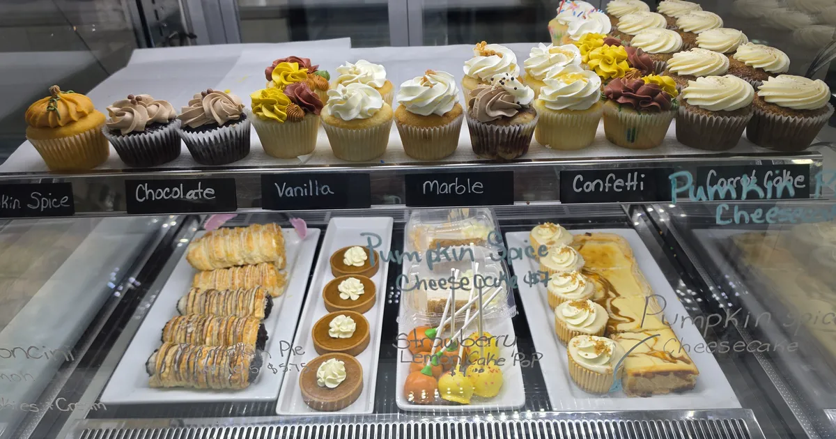 The Sweeterie display case: a row of cupcakes above trays of cannoli, tarts, cake pops and cheesecake.